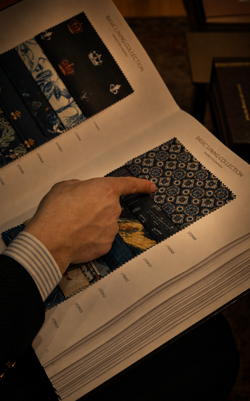 Client pointing to a patterned printed lining swatch in an open lining collection book at Metropolitan Tailoring